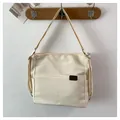 Minimalist off-white nylon tote bag with dual front pockets and durable shoulder strap - Black