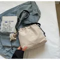 Détail du sac seau beige à cordon avec étiquette KOKO et pendentif en peluche - Avec Pendentif / Blanc Cassé