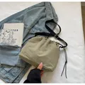 Détail d'un sac seau en nylon olive avec cordon de serrage sur fond de veste en jean - Sans Pendentif / Vert