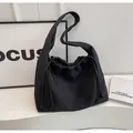 Vue détaillée d'un sac à bandoulière noir à cordon sur un décor de table blanc - Noir