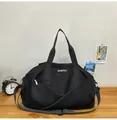 Bolsa de viaje negra grande con correa al hombro y logo blanco sobre mesa de madera - Negro