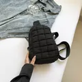 Black quilted nylon crossbody chest bag with adjustable strap on denim jacket background - Black