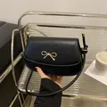 Borsa a sella minimalista in pelle nera con fibbia decorativa a fiocco dorato - Nero