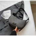 Dettaglio della trama intrecciata bianca e nera di una borsa a mezzaluna con logo dorato - Nero senza Ciondolo