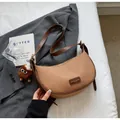 Détail du sac croissant tissé avec bordure en cuir et peluche sur une veste grise chic - Khaki Avec Pendentif