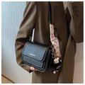 Detail of black crossbody bag with double flap, polka dot scarf, and plush charm - With Pendant / Black