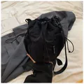 Minimalist black nylon drawstring bucket bag with mesh side pockets and crossbody strap - Black