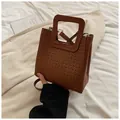 Détail d'un sac seau tressé marron avec des poignées carrées et une bandoulière amovible - Marron