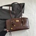 Sac cabas en cuir marron foncé avec logo doré et charme de corde tressée sur blanc - Avec Pendentif / Marron