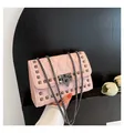Lichtroze gewatteerde crossbodytas met metalen klinknagels en ketting op zwart hout - Roze