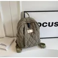 Detail of quilted olive green backpack showing diamond stitching and adjustable strap - Green