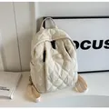 Detail of cream quilted backpack featuring puffy diamond lattice texture and side pockets - White