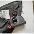 Detalle del bolso denim con ribete de cuero, remaches metálicos y colgante de pompón negro - Marrón & Negro Pequeño