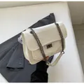 Sac bandoulière blanc à surpiqûres en V et chaîne argentée sur fond de blazer noir - Blanc Cassé