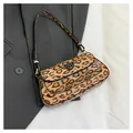 Sac baguette léopard chic avec détails argentés posé sur une veste de costume grise - Kaki