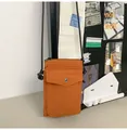 Detalle de un bolso bandolera naranja de nailon con cierre a presión y correa negra - Marrón