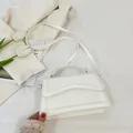 Minimalistische cremeweiße Umhängetasche aus Leder mit eleganter Wellenklappe und Griff - Weiß