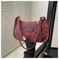 Red and black leopard print baguette bag with crescent shape and gold zipper detail - Red
