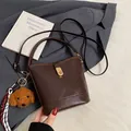 Dark brown leather bucket bag with retro texture, gold lock, and cute plush dog charm - With Pendant / Coffee