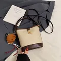 Chic cream and brown color-block bucket bag with plush charm and gold hardware - With Pendant / Beige
