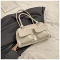 Detail of a creamy beige leather rectangular handbag with dual front pockets on fabric - Off White