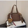 Deep brown lychee textured leather handbag with a plush bear charm and long strap - Coffee