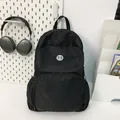 Minimalist black quilted nylon backpack for commute featuring a round logo and mesh side pockets - Standard Type / Black