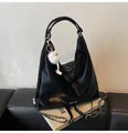 Gros plan d'un sac hobo en cuir poli noir avec bandoulière chaîne et pompon en peluche - Avec Pendentif / Noir