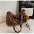 Close-up of brown leather tote bag with FASHION & BAGS tag and cute bear pendant - Brown