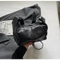 Close-up of black leather underarm bag with silver zipper and rivet details on the handle - Black