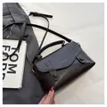 Detailed view of dark brown leather satchel with metal buckle and adjustable strap - Black