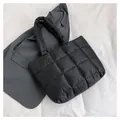 Chic black quilted puffer tote bag with large square stitching on a minimalist background - Black