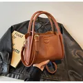 Vintage brown leather crossbody bag with dual handles and gold hardware details - Brown