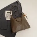 Retro bruine leren draagtas met kettingdetail en honkbalbedel op een grijze blazer - Grijs Met Hanger