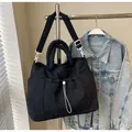 Black wave-quilted nylon tote bag with adjustable shoulder strap and drawstring pockets - Black