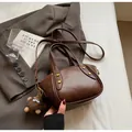 Dark brown leather bucket bag with gold hardware and plush monster charm accessory - Brown