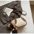 Chic beige and brown leather bucket bag with gold rivets and cute plush monster charm - Off White