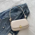 Chic cream white underarm flap bag with gold M-buckle on a denim jacket background - White