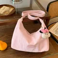 Pink crescent shoulder bag with pleated texture and cute plush charm on a wooden table - Pink With Pendant