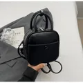 Detail eines schwarzen matten Mini-Rucksacks aus Kunstleder mit Doppelgriffen und Fronttasche - Schwarz ohne Anhänger