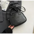 Minimalist black patchwork leather crossbody pillow bag with top handles and gold lettering - Black