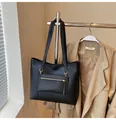 Macro shot of black tote bag featuring front zipper pocket and gold hardware detailing - Black