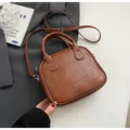 Brown vintage Boston bag with textured grid stitching and dual handles on a white desk - Brown