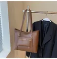 Detail of a brown leather tote bag showing a front zipper pocket and fine stitching details - Brown