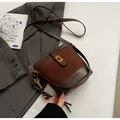Détail d'un sac seau en daim marron avec fermoir doré et bandoulière en cuir - Café Avec Pendentif Lapin