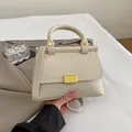 Minimalist beige lychee grain leather handbag with gold metal lock and circular handle - White