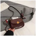 Sacoche selle bordeaux effet crocodile avec pendentif ours sur un manteau gris - Avec Pendentif / Café