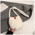 Detail of soft white faux fur crossbody bag with red plush ball on winter coat - White