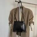 Détail d'un sac à bandoulière bohème noir à franges suspendu à un support métallique - Cuir PU Noir