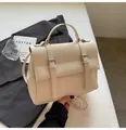 Detailed macro view of cream leather texture and silver buckle straps on the handbag - White